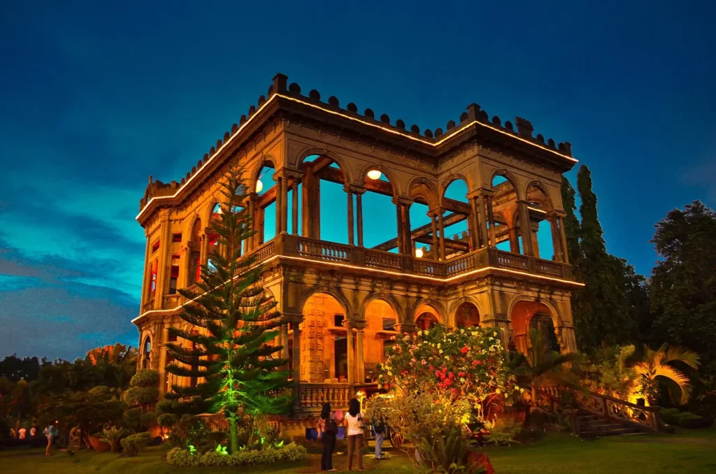 A colonial-style mansion with grand arches and detailed architecture, set in a vibrant garden.